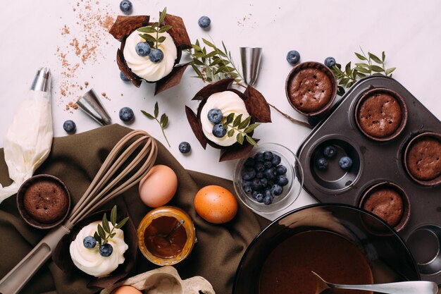 Photo cupcakes with cream and blueberries on kitchen table