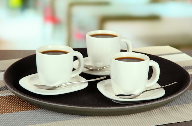 Cups of coffee on tray on table in cafe