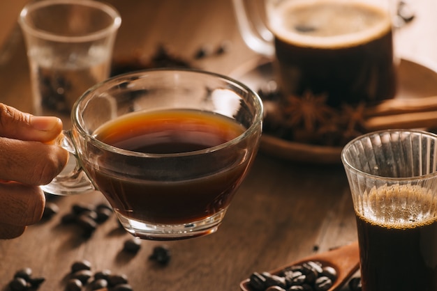 Cups of coffee with coffee beans on wooden surface