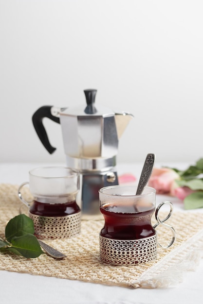 Cups of fresh coffee and coffee maker on white table