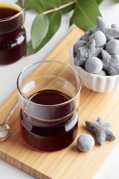 Cups of fresh coffee and a liquorice candies on white table