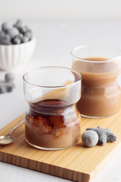 Cups of fresh coffee with milk and a liquorice candies on white table