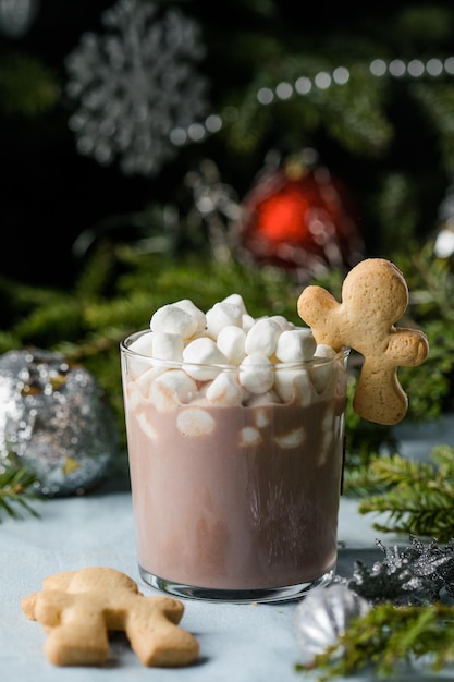 Cups of hot chocolate drink with marshmallows and cinnamon on brown wooden background