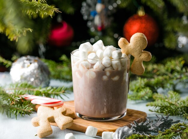 Cups of hot chocolate drink with marshmallows and cinnamon on brown wooden background