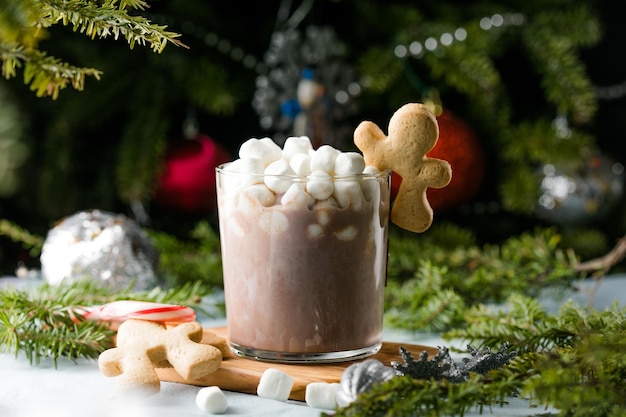 Cups of hot chocolate drink with marshmallows and cinnamon on brown wooden background