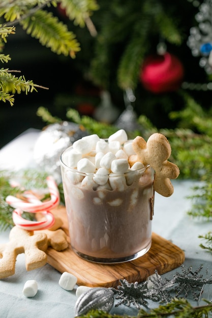 Cups of hot chocolate drink with marshmallows and cinnamon on brown wooden background