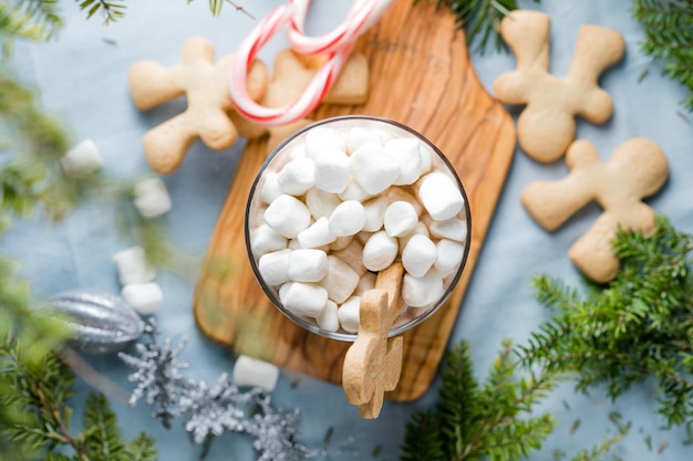 Cups of hot chocolate drink with marshmallows and cinnamon on brown wooden background