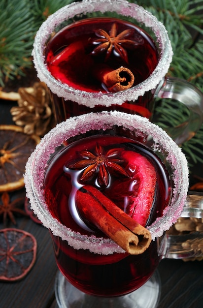 Cups of mulled wine spices and dry citrus fruits on a wooden table top view warming christmas drink close up