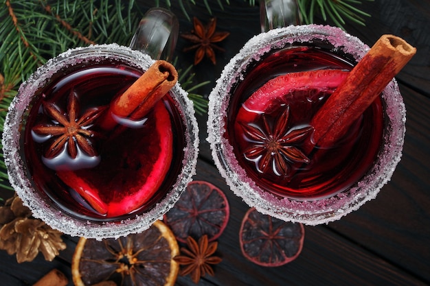 Cups of mulled wine spices and dry citrus fruits on a wooden table top view warming christmas drink close up