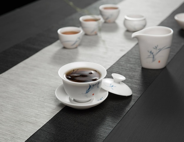 Cups of tea and a cup of tea are on a table with a white and black table cloth.