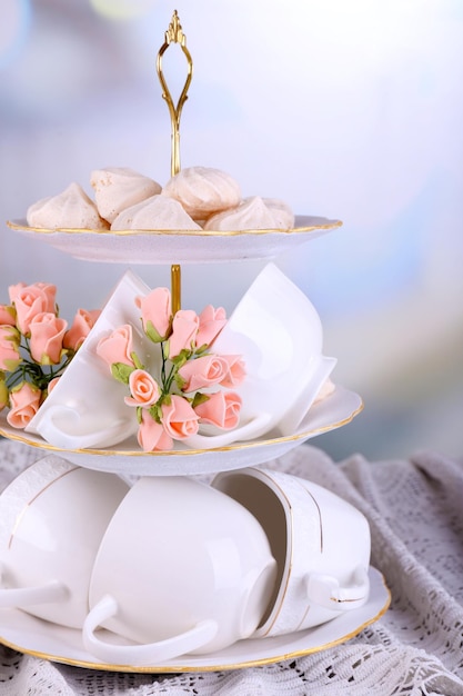 Cups in vase on table on bright background