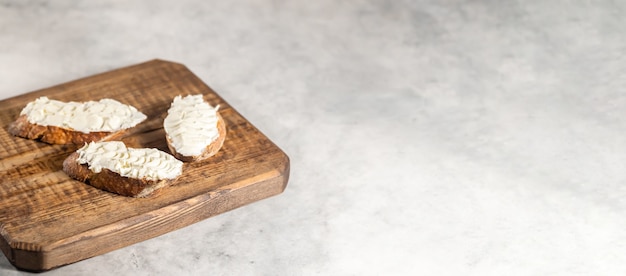 Curd cream cheese sandwiches on wooden board. Space for text, selective focus, sandwich banner grey background.