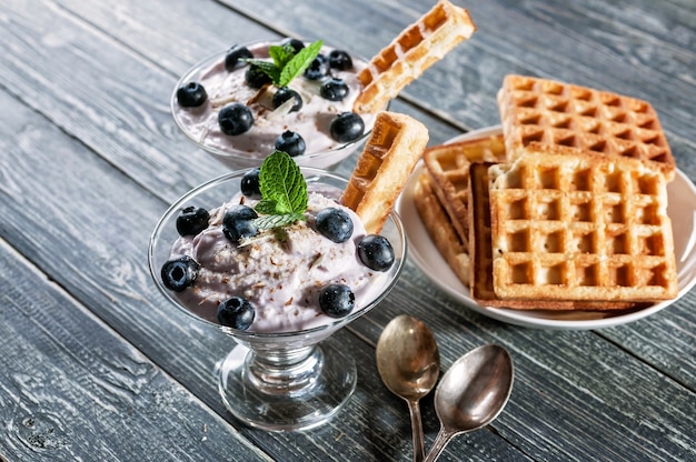 Curd dessert with blueberries in a glass cup and homemade Viennese waffles