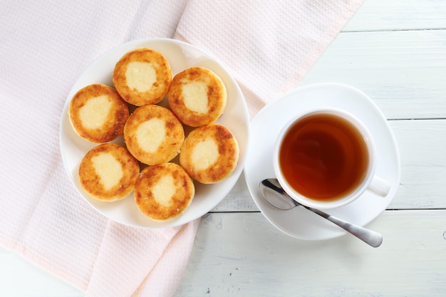 Curd fritters with tea Traditional breakfast Food on a bright table