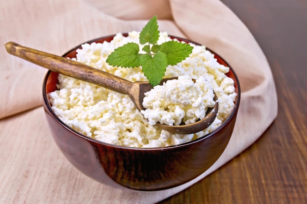 Curd in wooden bowl with spoon on napkin and board