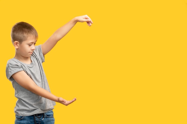 Curious kid Advertising background Special offer Sale discount Portrait of inspired happy young boy holding looking at invisible product in open hand isolated on orange copy space