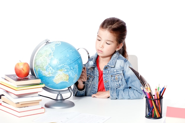 Curious little girl looking through magnifying glass on globe