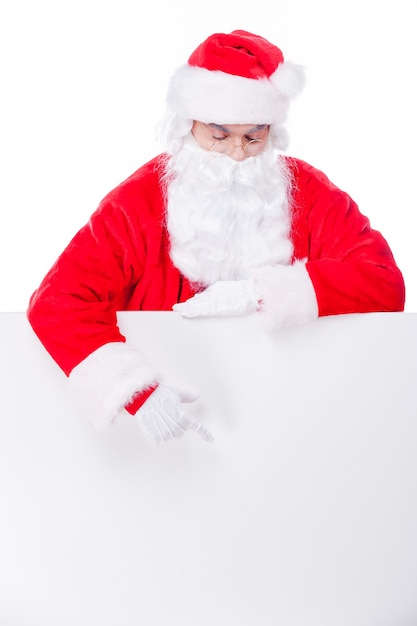 Curious Santa. Traditional Santa Claus pointing copy space while standing against white background