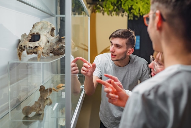 Curious young people observing animal skeletons and skulls displayed in a showcase during natural