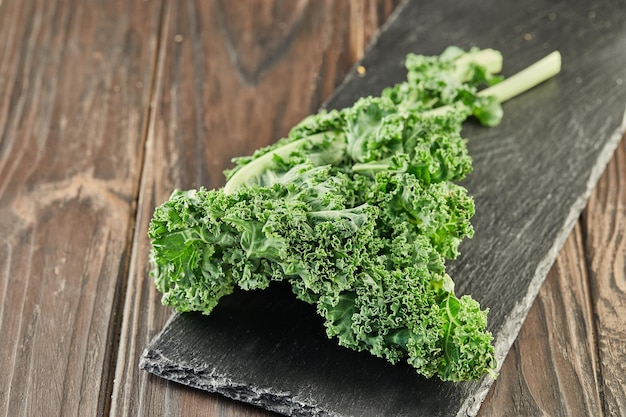 Curled lettuce on black stone on wooden background