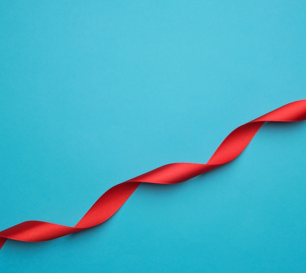 Curled red satin ribbon on blue background