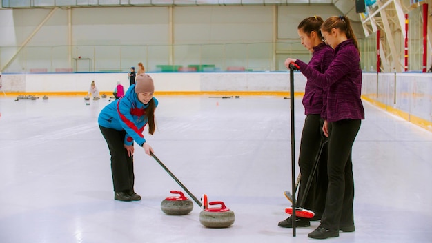 Curling training  the judge measuring the distance between two stones on the ice rink