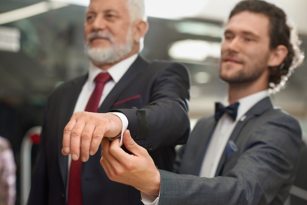 Curly brunette salesman helping costomer choosing jacket. 