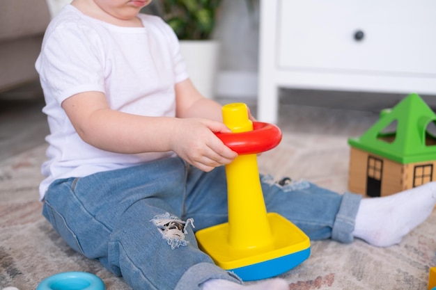 Curly child girl playing with pyramid and constructor at home early children development