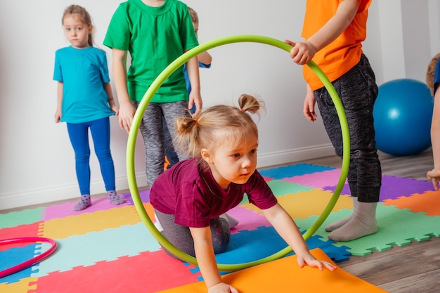 Curly girl crawling on colorful floor through hula hoops