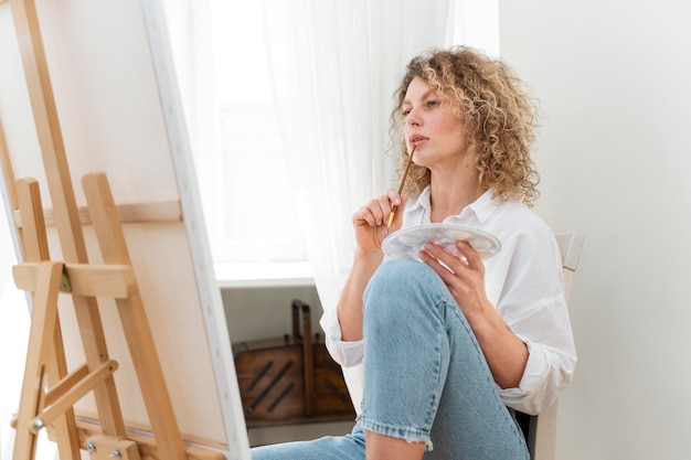 Curly-haired blonde woman painting at home