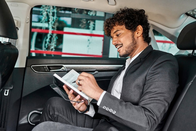 Curly-haired businessman writes down data in a notebook