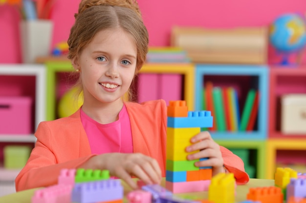 Curly little girl playing with colorful plastic blocks