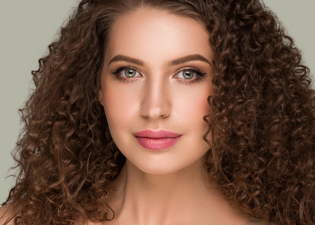 Curly long brunette hair woman beauty portrait, female glamour face. Color backgound green