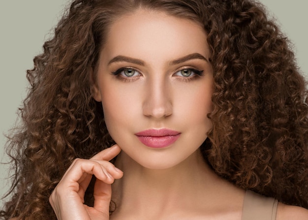 Curly long brunette hair young  woman touching face beauty  female portrait. Color backgound green