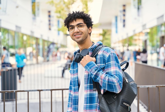 Curly middle eastern smiling man with braces  standing on the street. Portrait of happy tourist