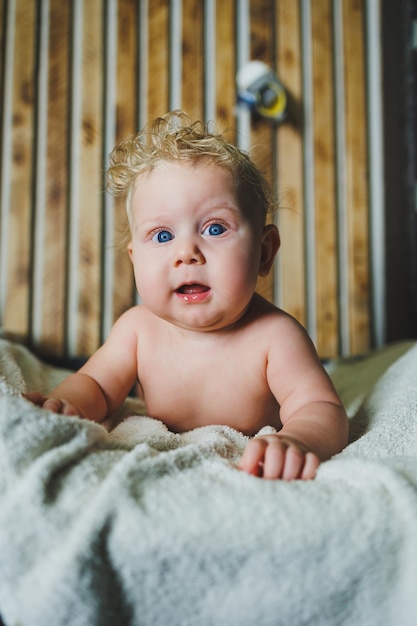 Curly newborn baby boy lies on a white towel after bathing Portrait of a 6monthold baby with a smile on his face