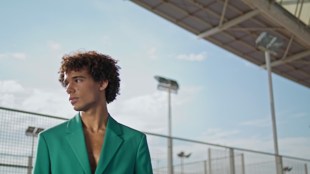 Curly student looking camera at stadium fashion portrait serious model posing