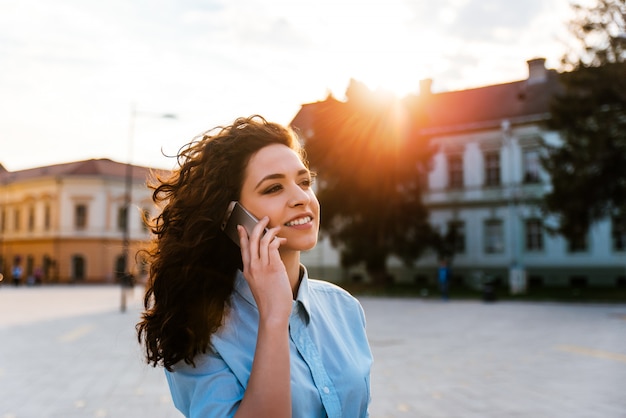 Curly teen using smartphone in the city