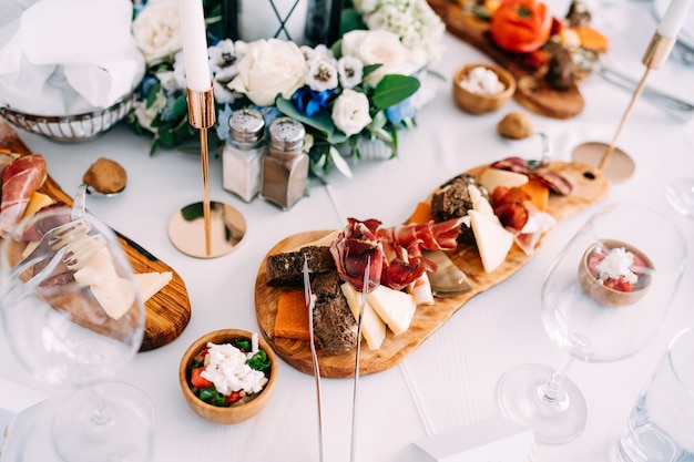 Curly wooden cutting board with slices of black bread prosciutto and cheese near a salt shaker with