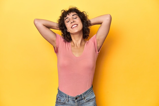 Curlyhaired Caucasian woman in pink tshirt stretching arms relaxed position