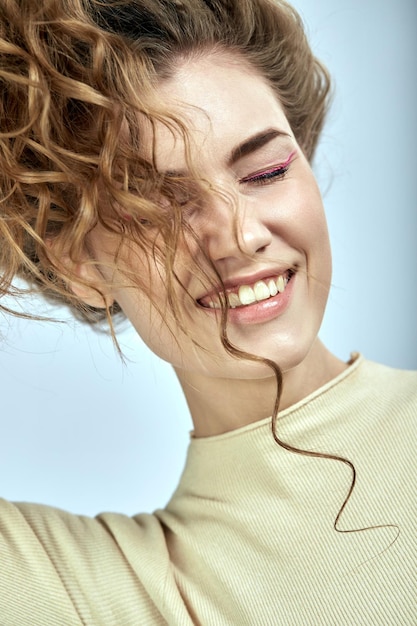 Curlyhaired girl is fooling around playing with her hair