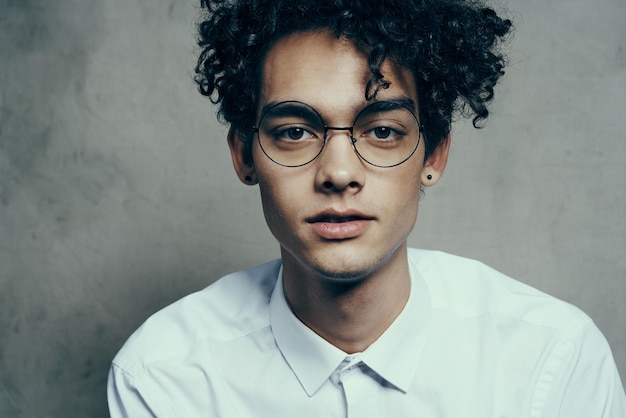 Curlyhaired man in glasses and in a white shirt on a fabric background smile model closeup portrait