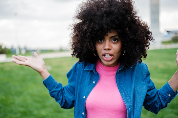 Curlyhaired young woman with an angry face asking for explanations outdoors at sunset