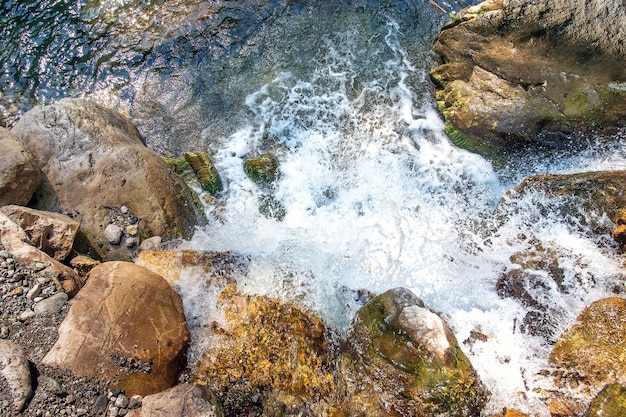 The current on the mountain river on the rapids forms a waterfall Blue water stones bright colo