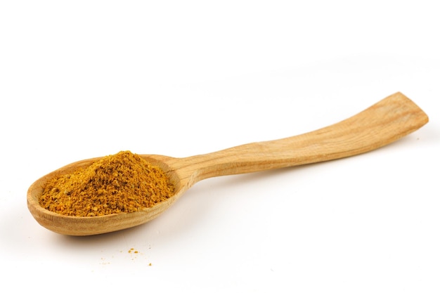 Curry powder seasoning in a wooden spoon isolate