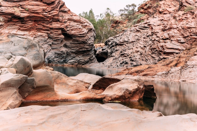 Curve and round rocks in an amazing gorge of Australia. Karijini's red iron rocks are one of the most ancient remains of the Earth when the seafloor got rusted by oxygen creating layers. Travel.