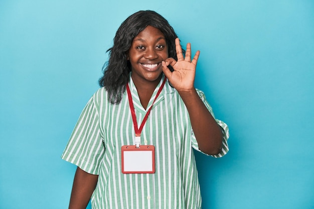 Curvy cashier with ID at supermarket cheerful and confident showing ok gesture