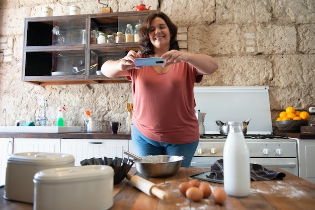 Curvy female foodie photographing what she has cooked to upload to social media