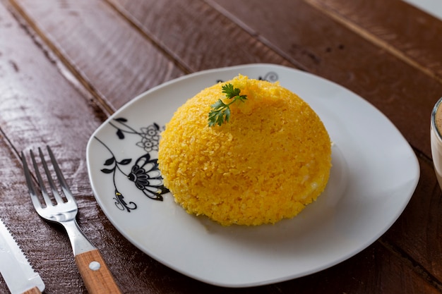 Cuscuz with cheese, typical northeastern food on a white plate and wooden table