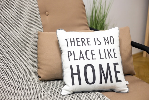 Cushions on a sofa with a text There is no place like home, living room interior design details